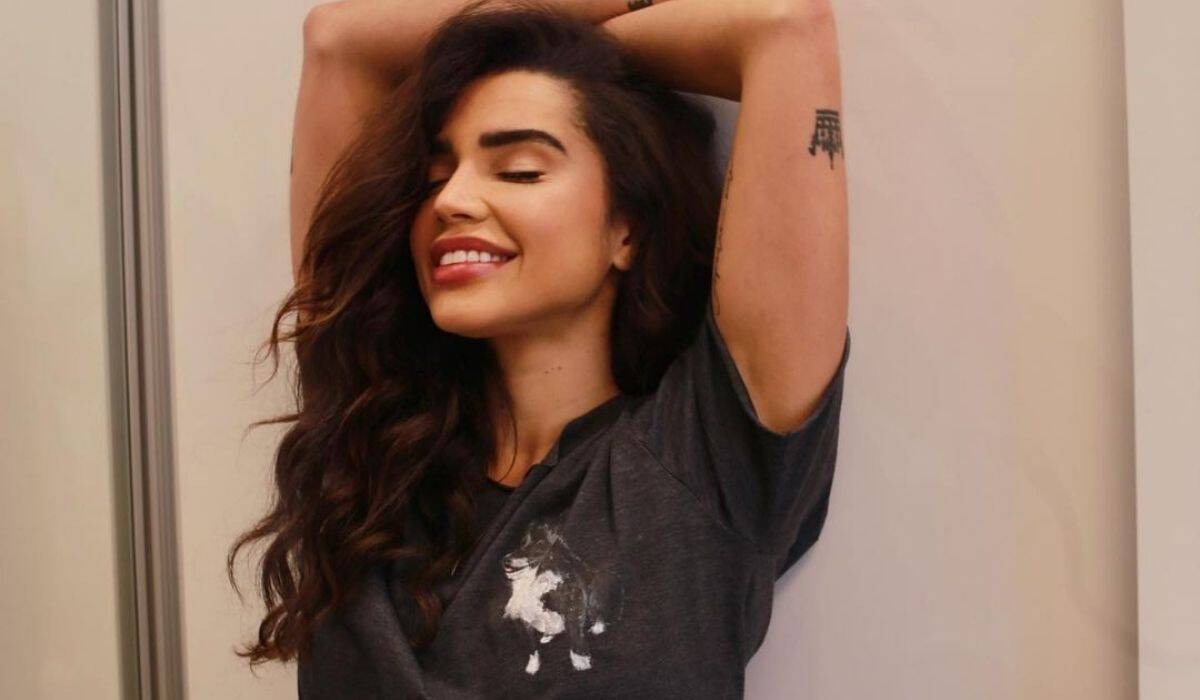 Paula Amorim posa apenas de camiseta e exibe tatuagem discreta